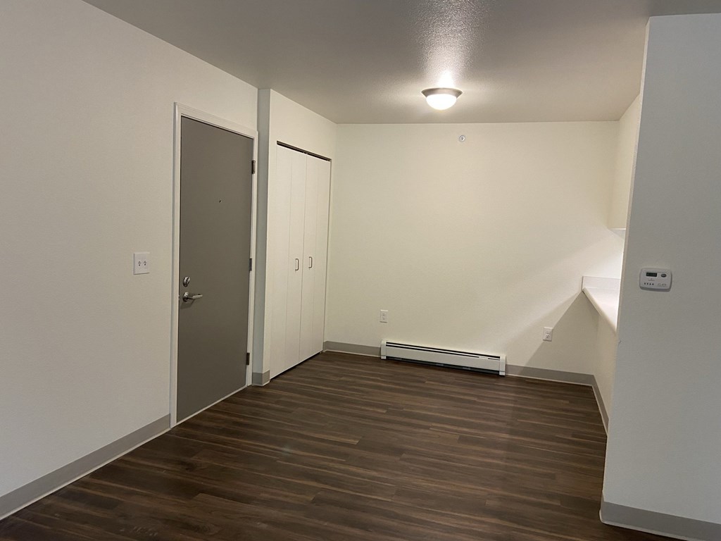 an empty living room with wood flooring and a door to a closet